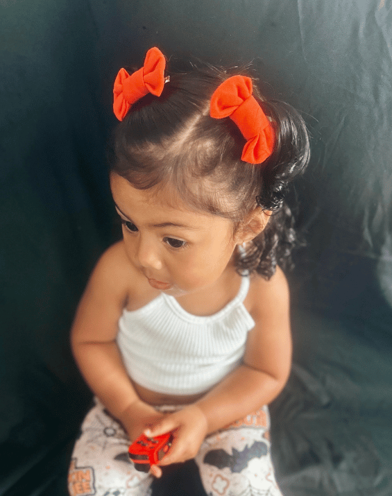 Little girl is wearing a set of bow clips for toddler girls from By Bella Boutique.