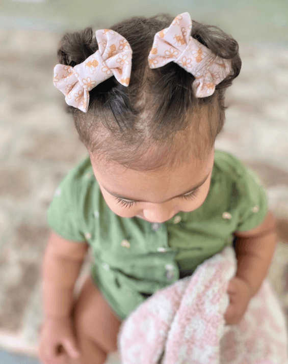 Little girl is wearing a set of handmade clips bows for toddler girls from By Bella Boutique.
