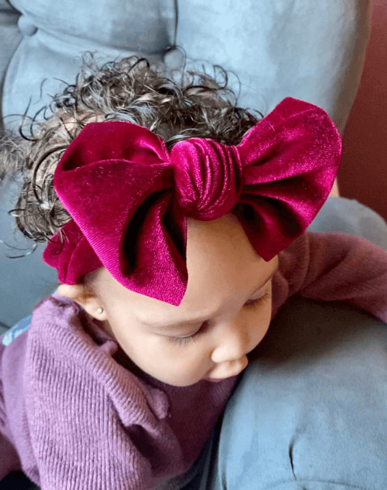 Baby girl is wearing a knotted headband for little girls from By Bella Boutique.