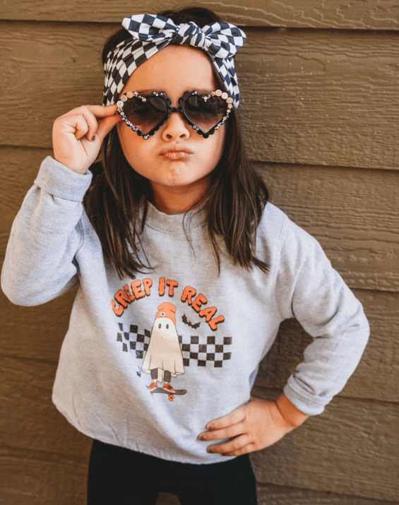 Toddler girl is wearing a comfortable headband featuring a checkerboard print for little girls from By Bella Boutique.