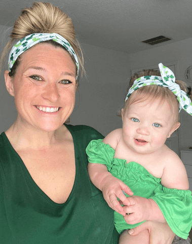 Mom and baby girl are wearing matching mommy and me head wraps from By Bella Boutique.
