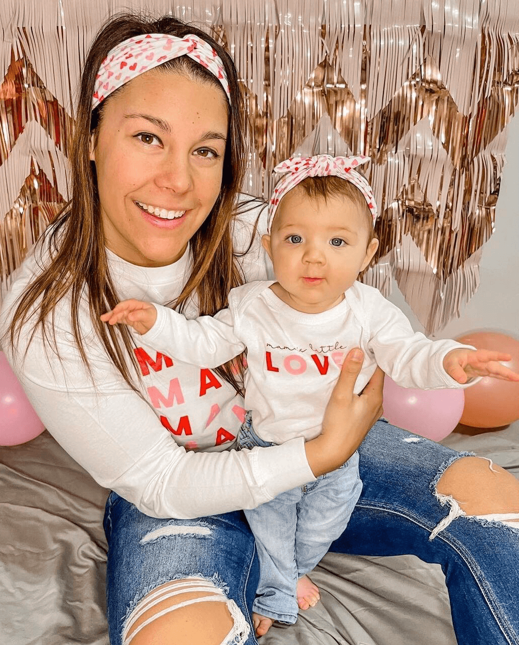 Mom and daughter are wearing a mommy and me heart print headband from By Bella Boutique.