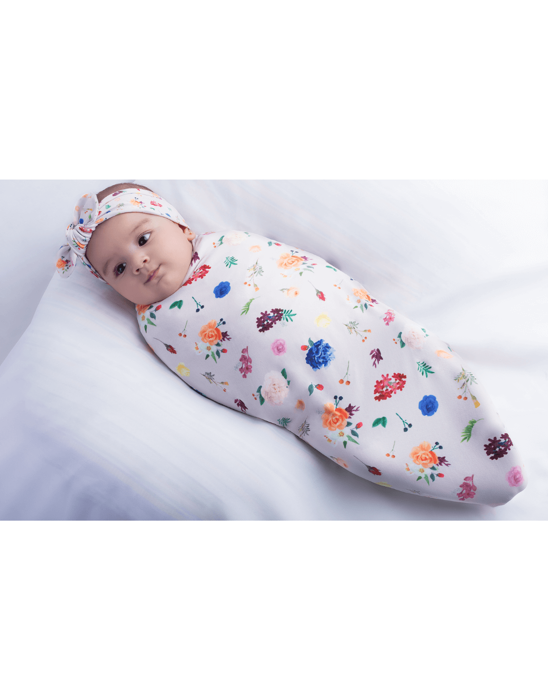 Newborn girl wearing a swaddle and bow set for babies from By Bella Boutiuqe.