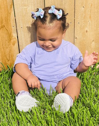 Little girl is wearing a pair of handmade clip bows featuring a mermaid pattern from By Bella Boutique.