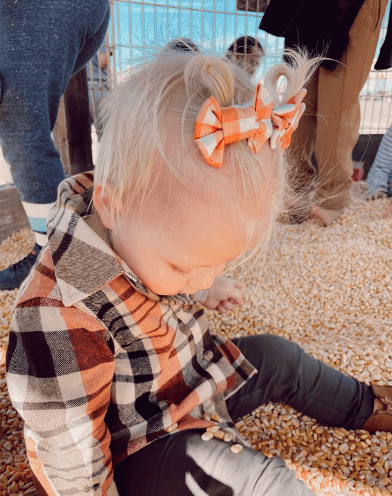 Toddler girl is wearing a pair of handmade clip bows from By Bella Boutique.