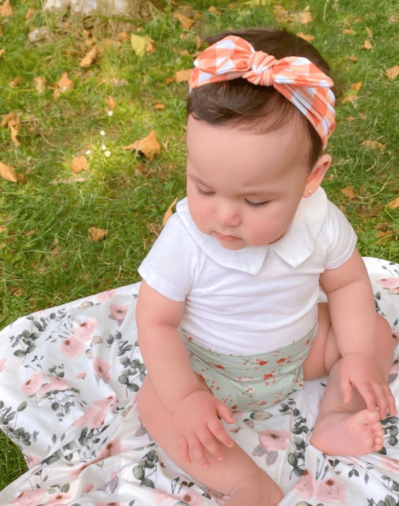 Baby girl is wearing a comfortable baby headband featuring a gingham print for little girls from By Bella Boutique.