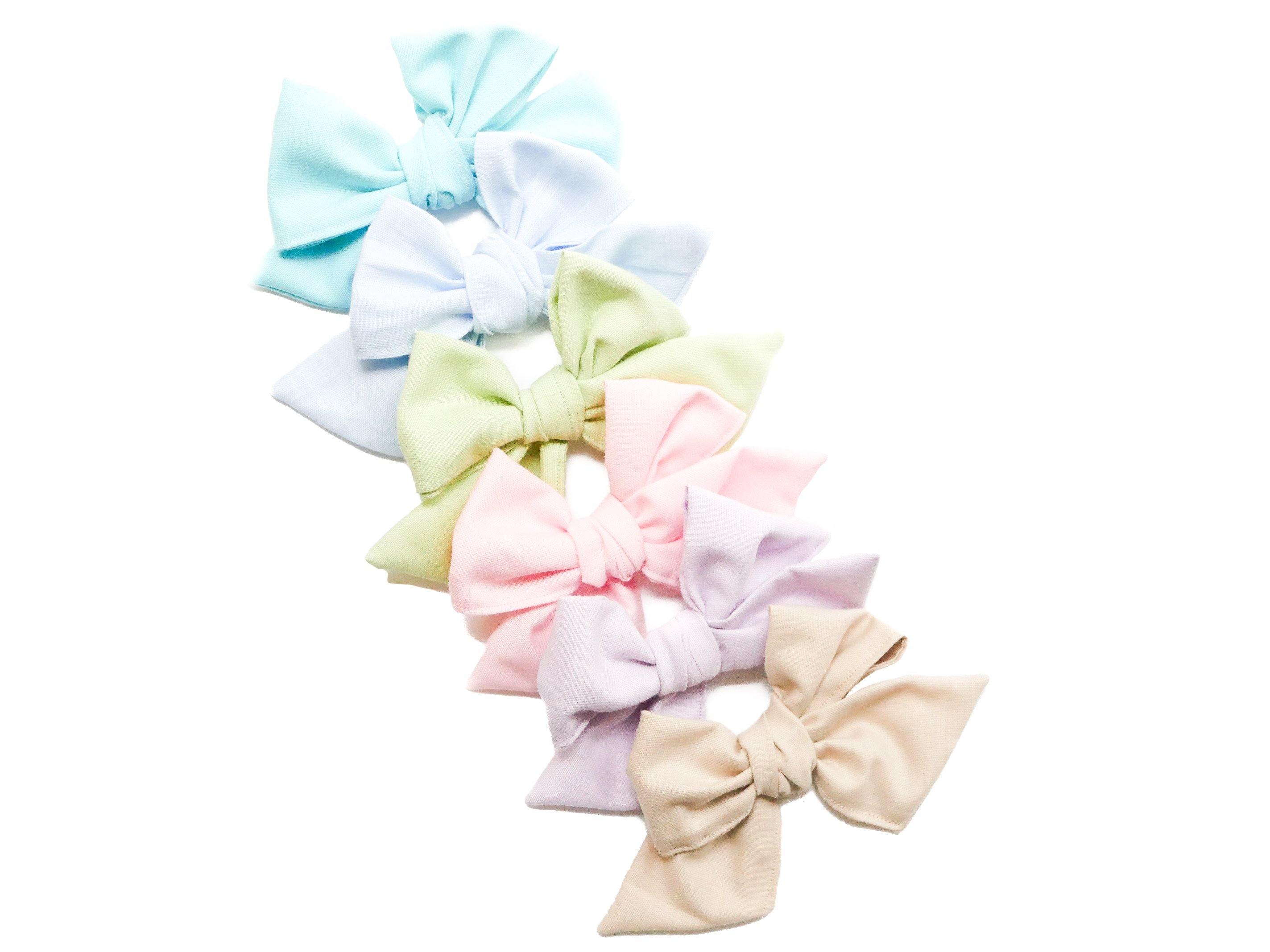 A collection of handmade linen pinwheel bows for toddler girls from By Bella Boutique.