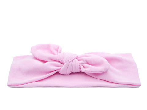 A pink knotted headband for little girls from By Bella Boutique.