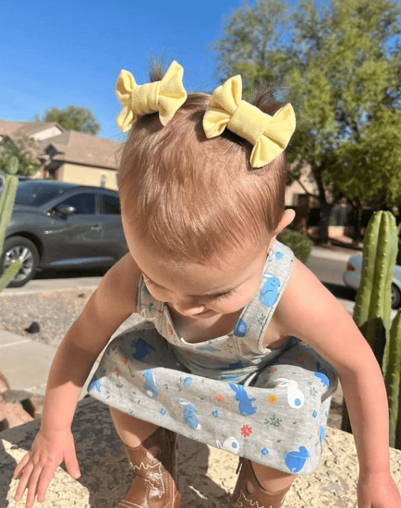 Baby girl is wearing a set of handmade bow clips for toddler girls from By Bella Boutique.