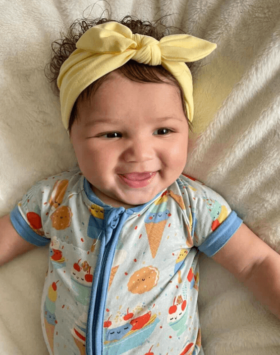 Baby girl is wearing a comfortable baby headband from By Bella Boutique.