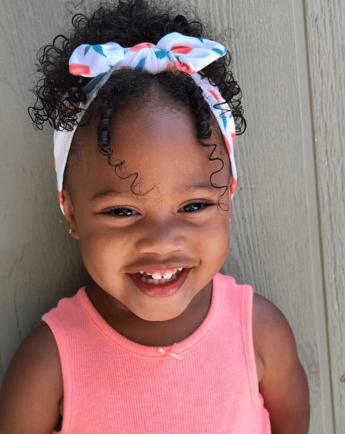 Toddler girl is wearing a knotted headband featuring a peach print from By Bella Boutique.