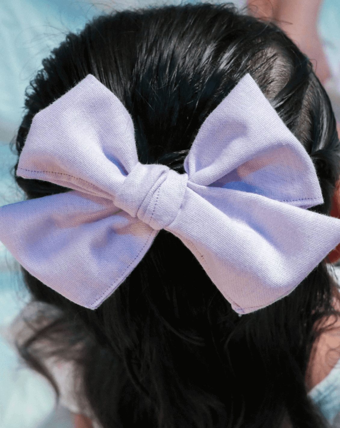 Toddler girl is wearing a handmade lilac pinwheel bow from By Bella Boutique.