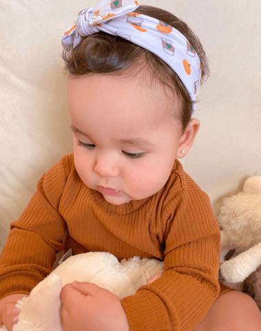 Baby girl is wearing a comfortable baby headband for girls from By Bella Boutique.
