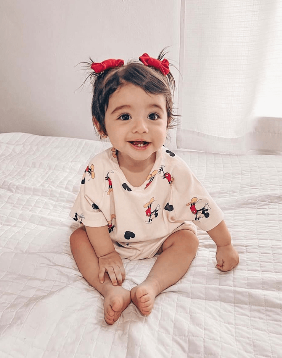 Toddler girl is wearing a pair of red bow clips from By Bella Boutique.