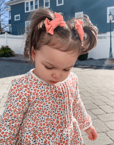 Toddler girl is wearing a pair of clips bows for toddler girls from By Bella Boutique.