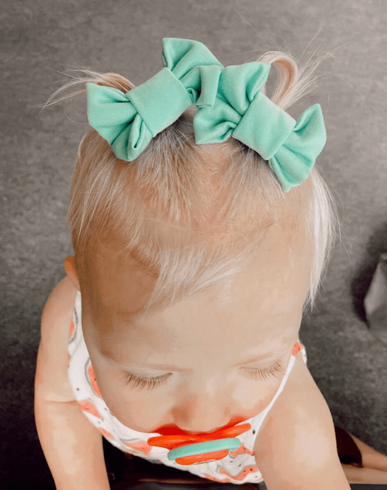 Toddler girl is wearing a set of handmade bow clips for toddler girls from By Bella Boutique.