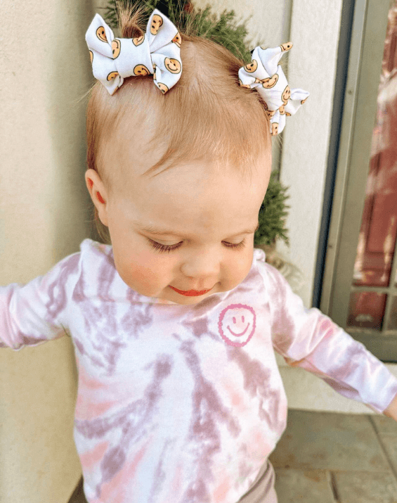 Little girl is wearing a pair of handmade clip bows from By Bella Boutique.
