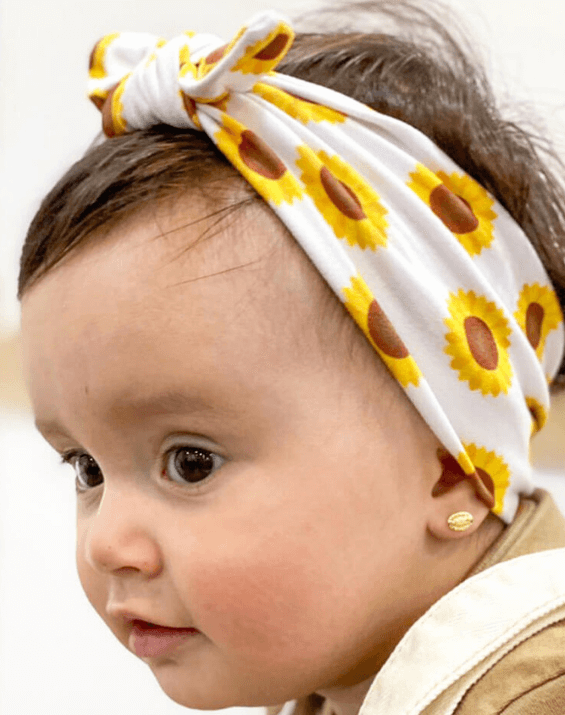 Toddler girl is wearing a handmade baby head wrap from By Bella Boutique.