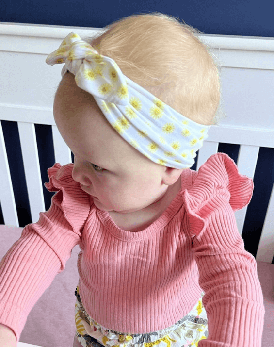 Baby girl is wearing the most comfortable headband from By Bella Boutique.