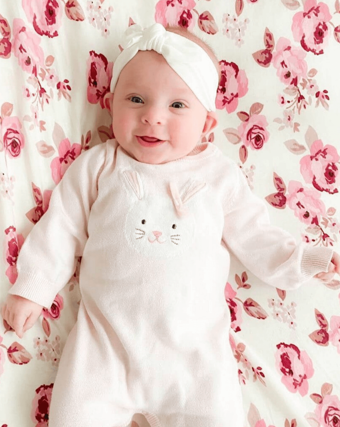 Baby girl is wearing a white baby head wrap for girls from By Bella Boutique.