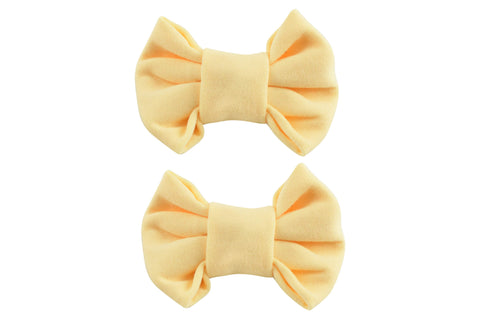  A pair of two pastel yellow bow clips for toddler girls from By Bella Boutique.