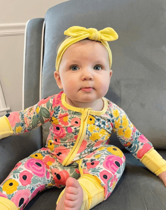 Baby girl is wearing a yellow knot headband for little girls from By Bella Boutique.