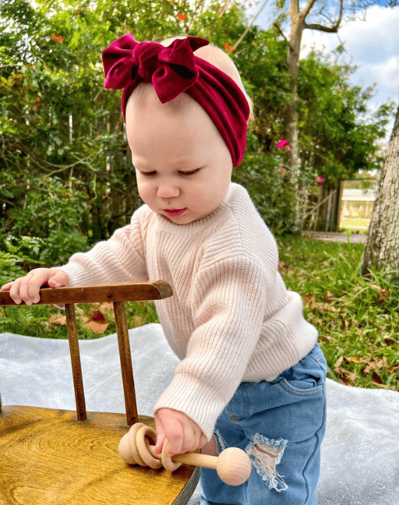 Baby girl is wearing a velvet head wrap from By Bella Boutique.